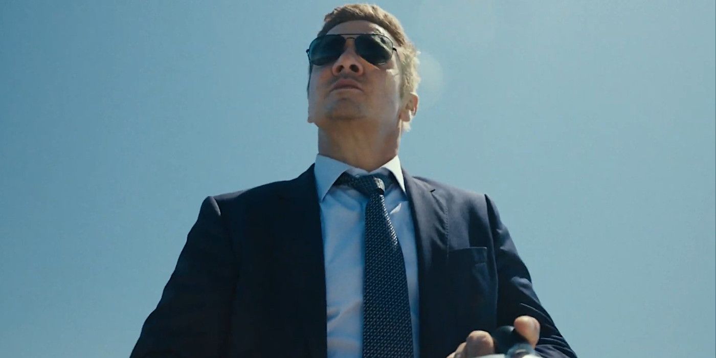 Jeremy Renner Kingstown Belediye Başkanı 2. sezonda mavi bir takım elbise ve güneş gözlüğü ile başının arkasında parlıyor.