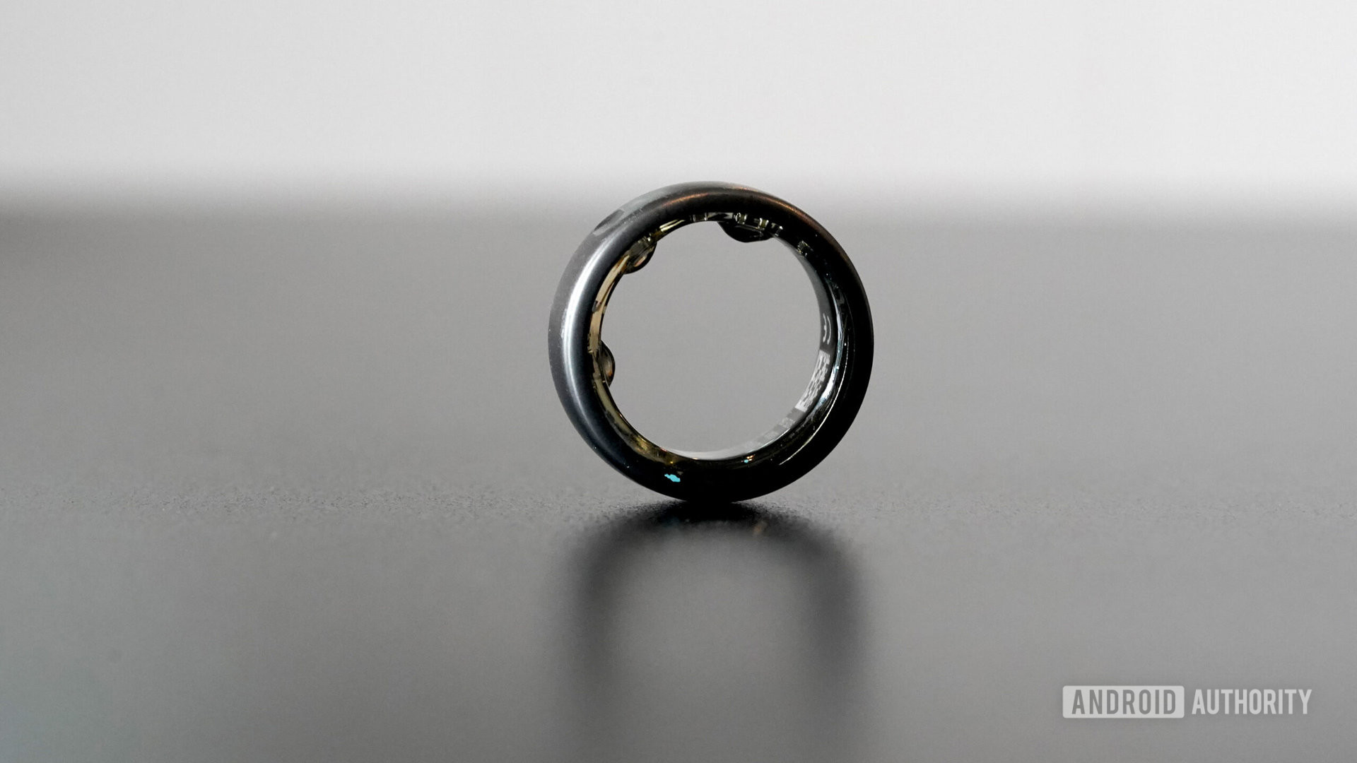 Gizli bir Oura Yüzüğü siyah bir yüzey üzerinde duruyor.