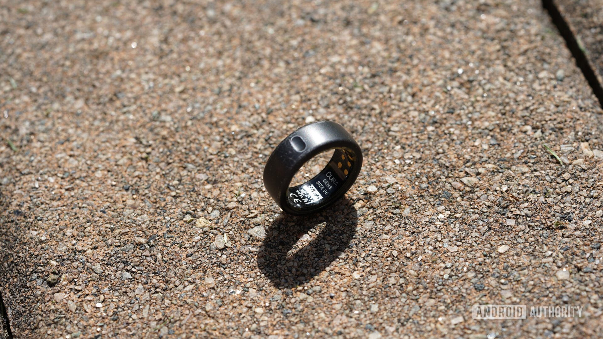 Oura Yüzüğü taş bir yüzey üzerinde duruyor ve Gen 3 etiketini gösteriyor.